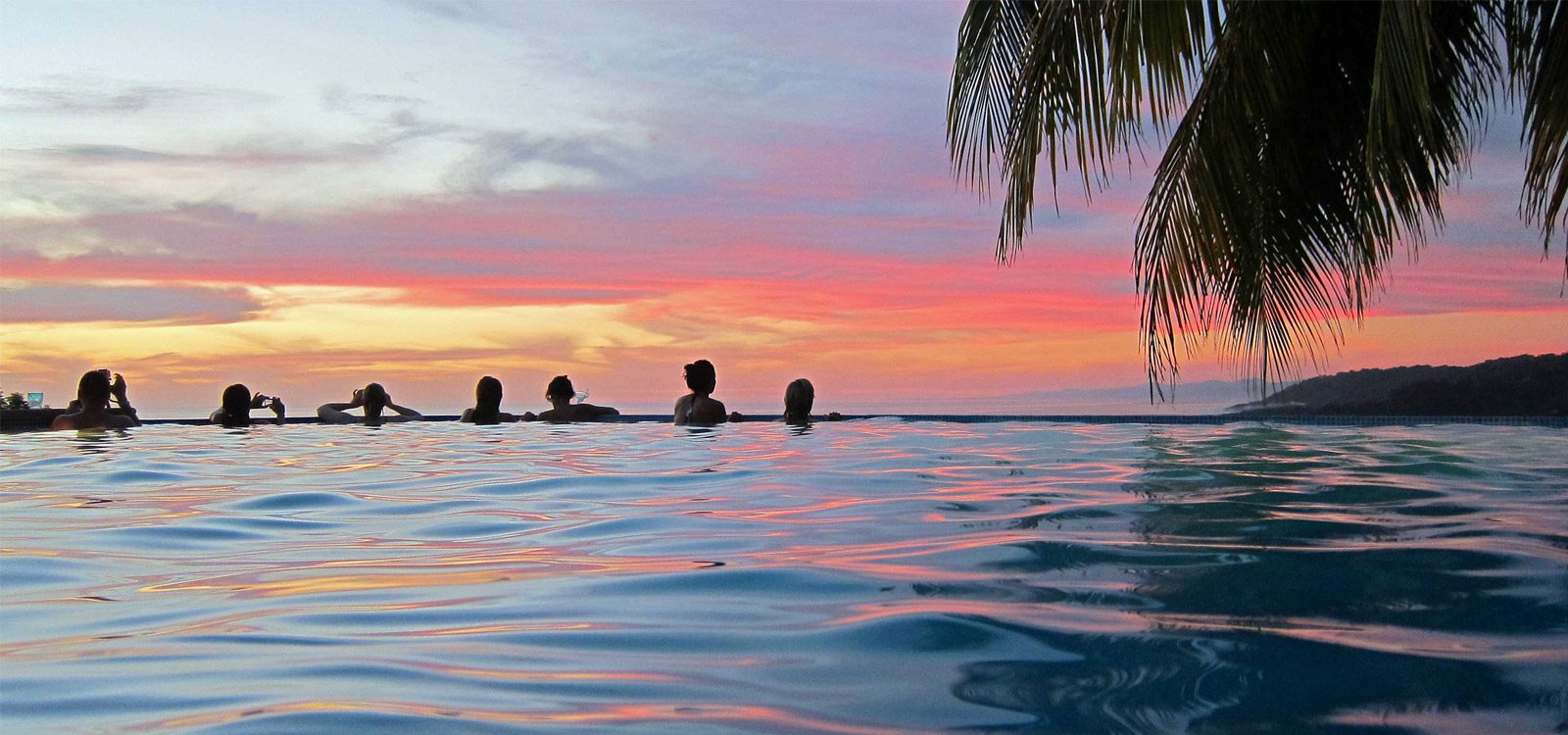 Group of Guests Relaxing At The Pool During Surf Retreat