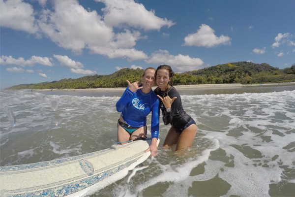 Women Doing the Shaka Sign and Surfing in Costa Rica