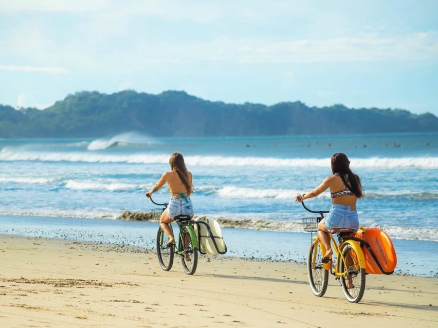 two women riding bicycles on the beach