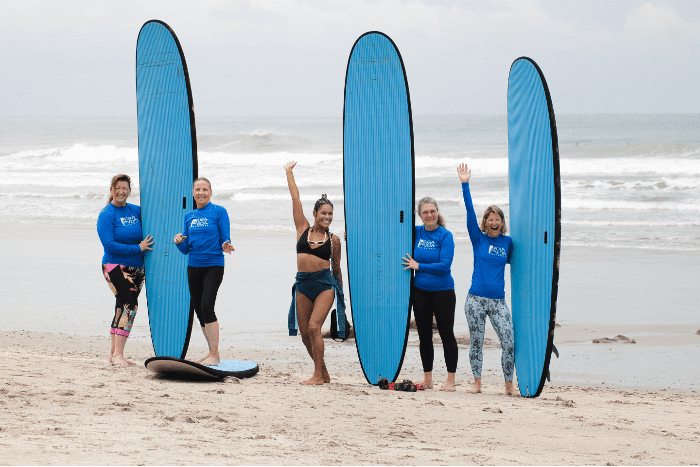 Beginner women surfers standing with longboards on the beach at a Costa Rica surf retreat
