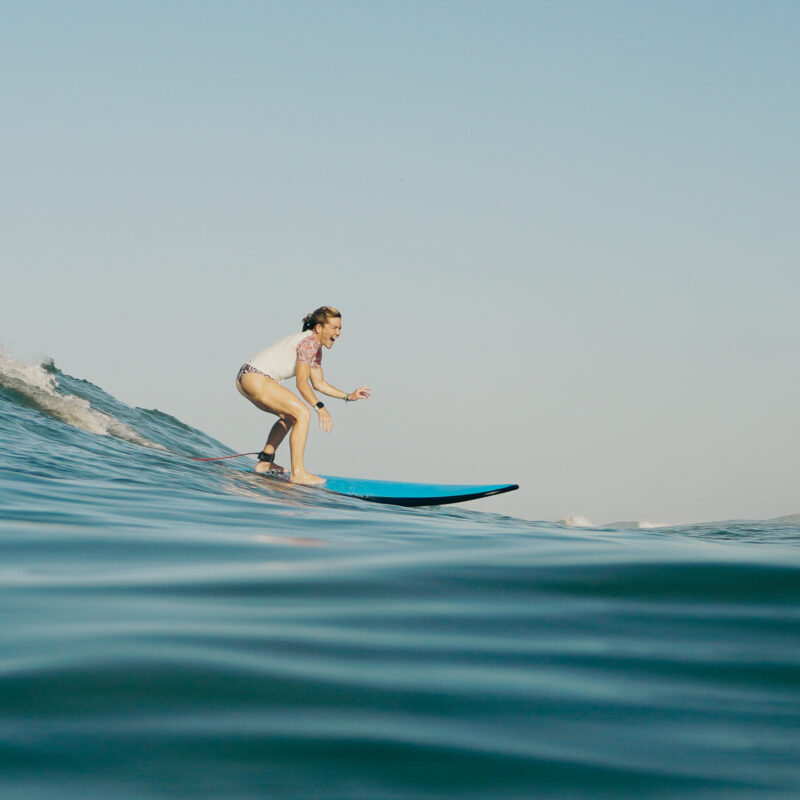 Woman over 50 surfing a wave at Pura Vida Adventures in Santa Teresa, Costa Rica