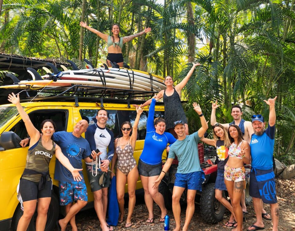 Pura Vida Adventures coed surf retreat group beside a vehicle loaded with surfboards in Costa Rica.